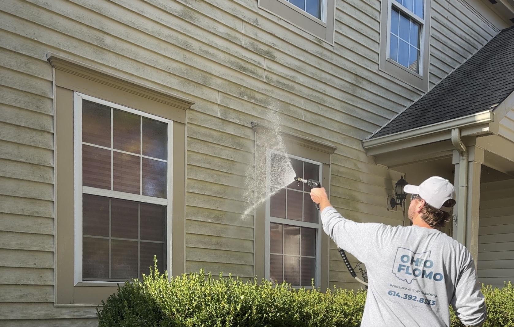 Owner Anton soft washing a residential home exterior for a thorough and safe clean by Ohio Flomo